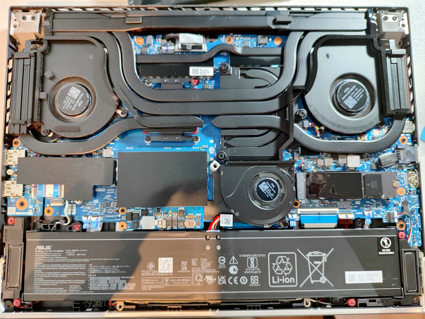 Laptop abierta en el banco del laboratorio, con disipadores y ventiladores a la vista